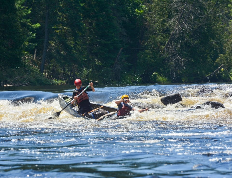 Image of 2 people paddling a canoe in rapids