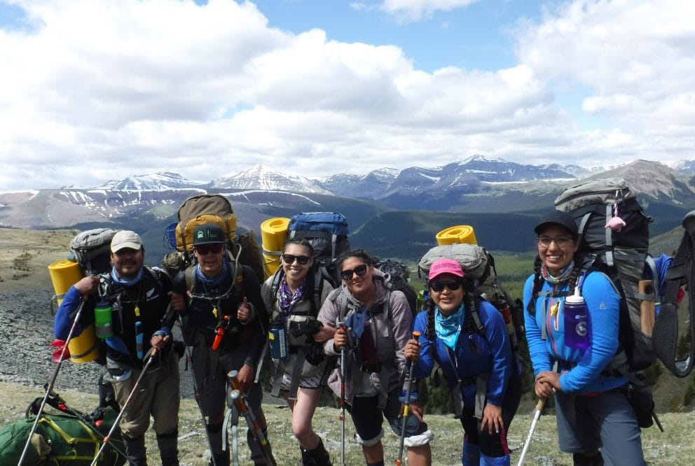 hikers smile at camera atop mountain