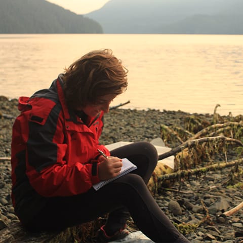 Maddy writing on the beach at sunset