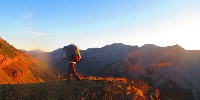 hiker walks along a ridge with mountains behind HEADER 1