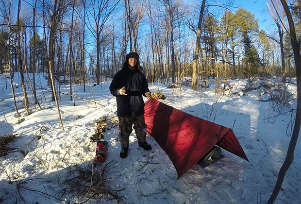 Image of a person standing near a tent in the snow