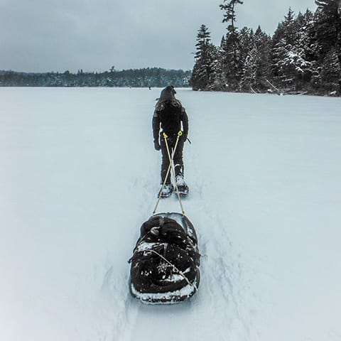 Image of person pulling a sled behind them over a frozen lake