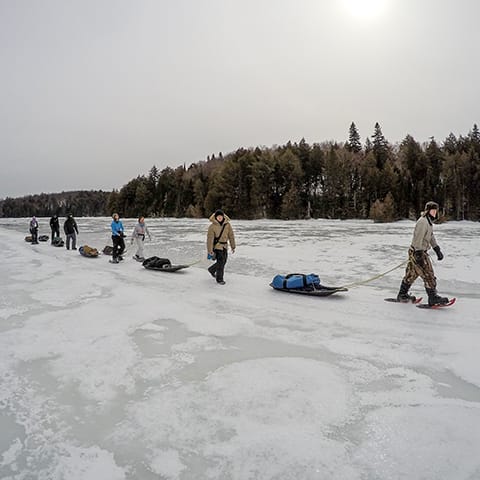 Image of a line of people pulling sleds across a frozen lake