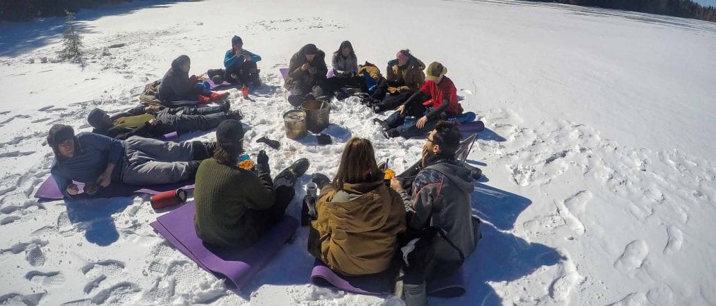 Image of a group of youth sitting in a circle on a snow covered lake