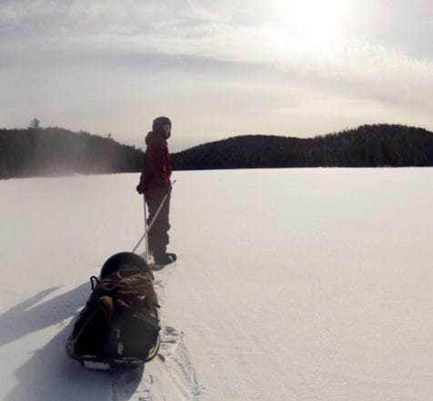 student pulling sled on winter lake
