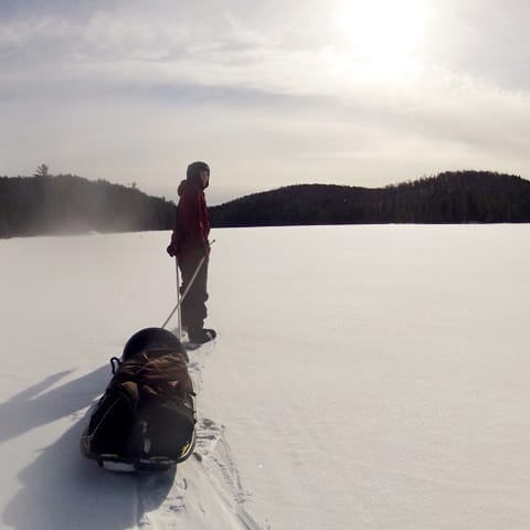 student pulling sled on winter lake