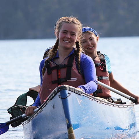 two smiling girls in blue canoe