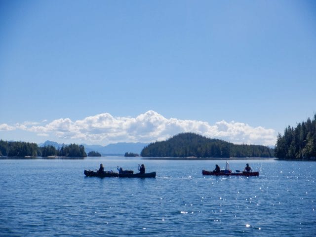 Image of two canoes paddling through an ocean inlet