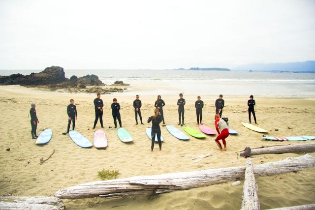 teens standing by surf boards on a beach