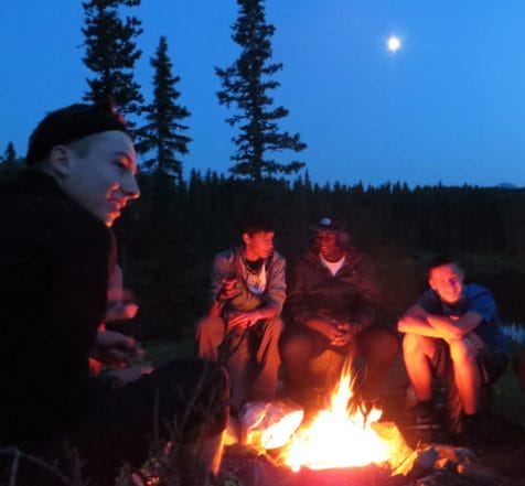 teens sitting by a fire in the moonlight