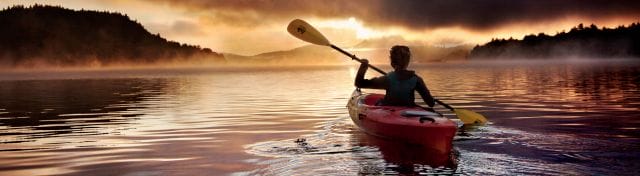 Person kayaking at sunset