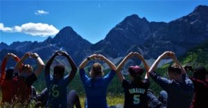 people making hearts with their hands with mountains in the distance