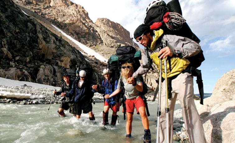 group of hikers crossing a river