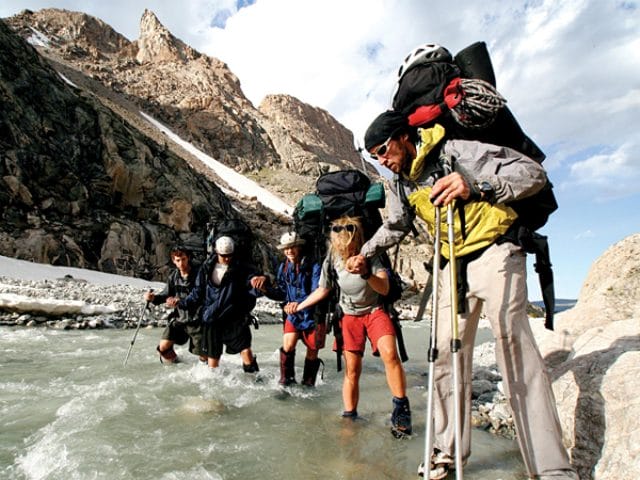 group of hikers crossing a river