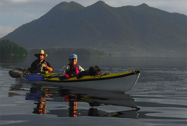 Image of 2 people in a tandem kayak on a still ocean
