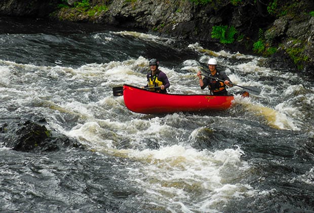 Image of two jolly people canoeing in whitewater