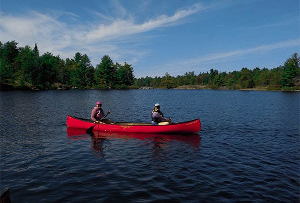 Image of two people paddling red canoe