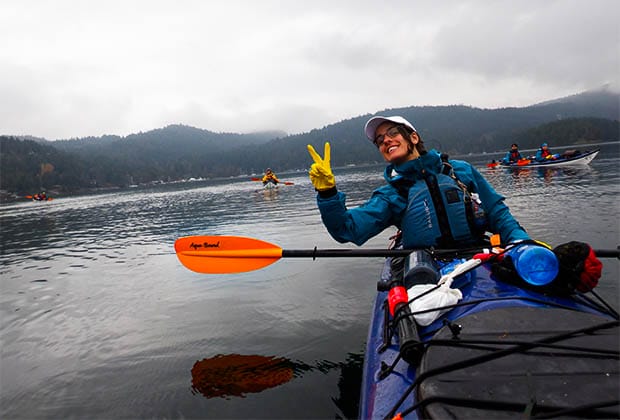 Image of a teen showing a peace sign while sitting in the kayak