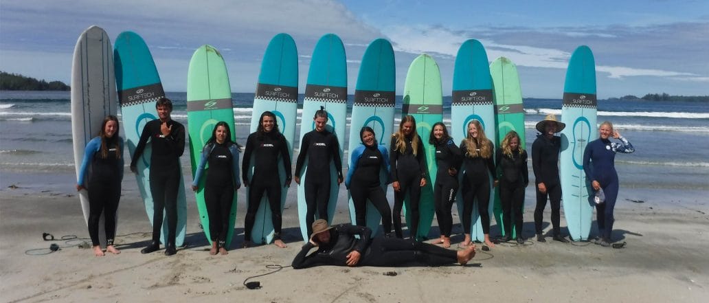 Image of a group of teens standing in front of their surfboards