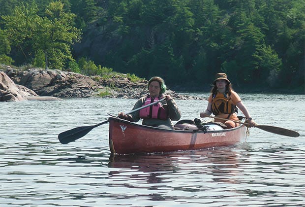 Image of two people paddling canoe