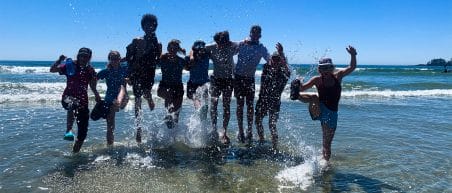Image of a group, jumping in the sea and splashing water