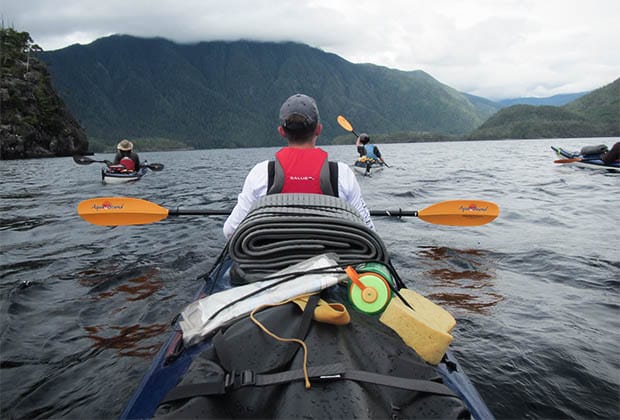 Image of a teen paddling a kayak into the coast mountains
