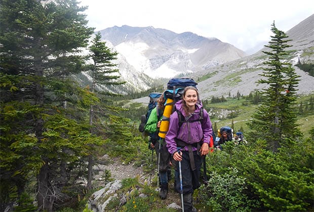Image of teen with backpack, hiking on a mountain with group