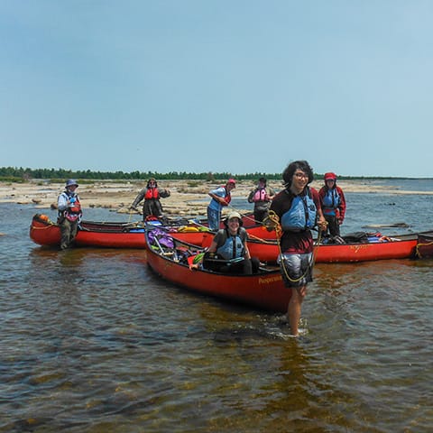 Image of group of youth and their canoes in shallow water