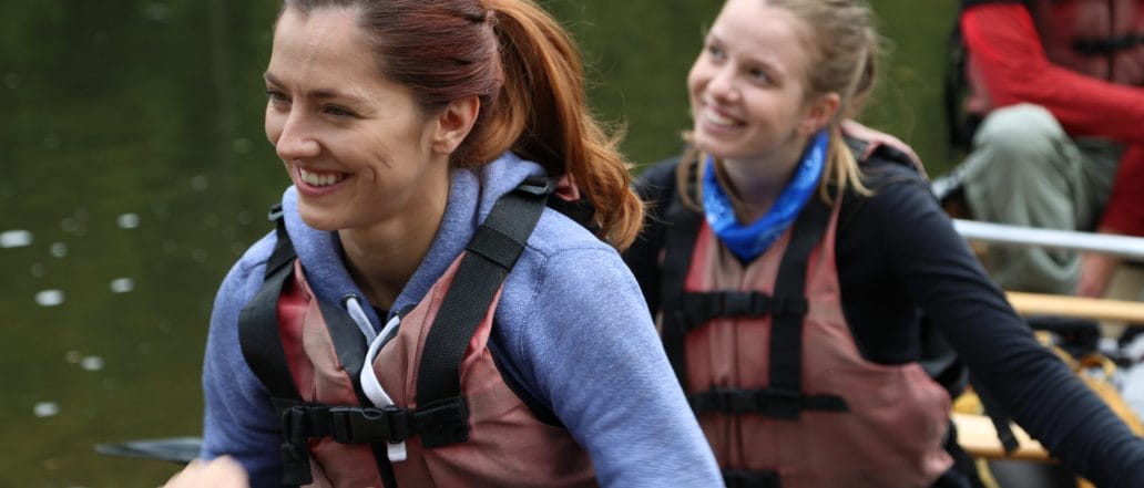 women smiling in canoe