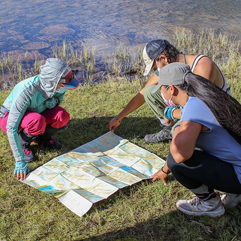 Image of three people crouched around a map