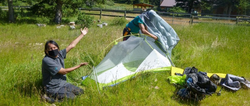 Image of two people putting a tent together