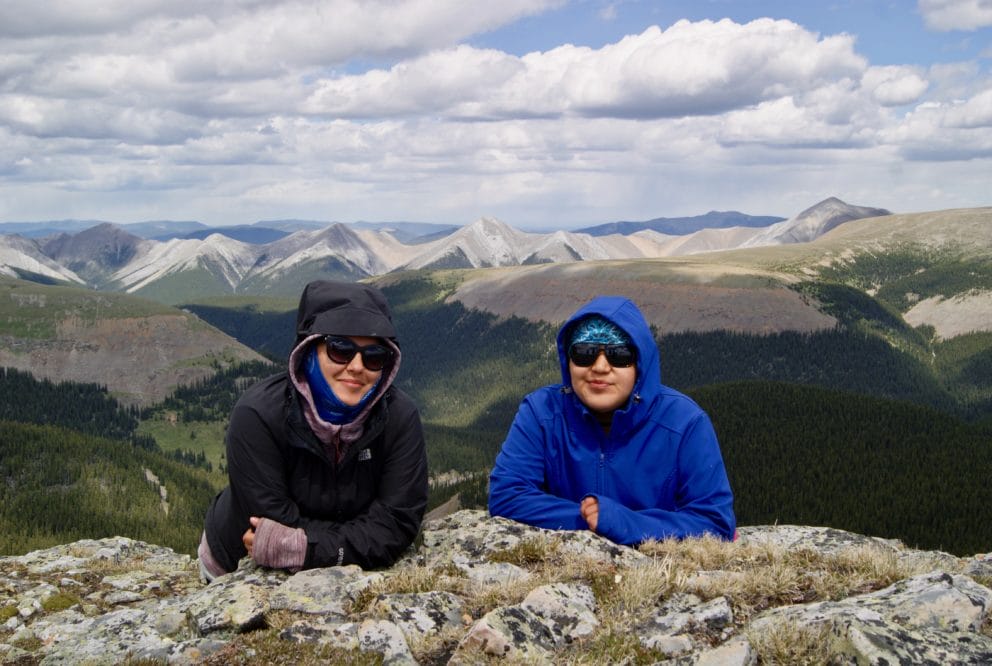 two people smiling in front of mountains