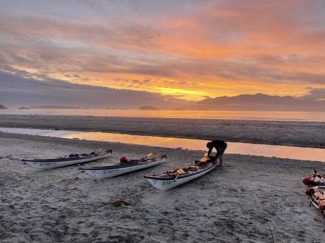 Image of kayaks on a beach at sunset