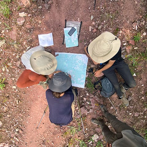 Image of three people sitting around a map laid out on the ground