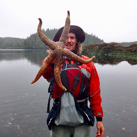 Image of a young adult holding up a large starfish