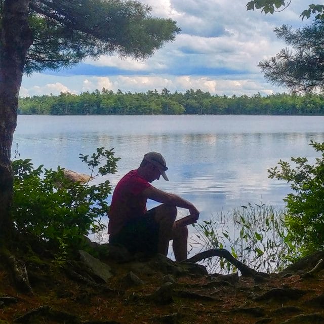 Image of a silhouette of a person sitting next to a lake