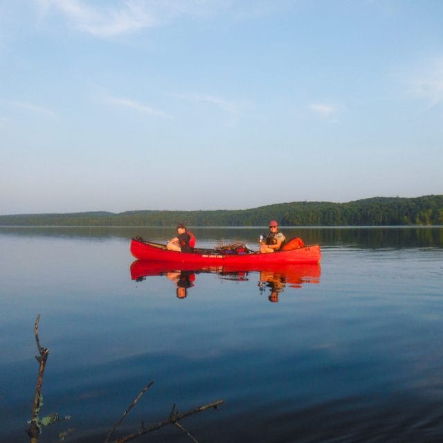 Image of 2 people in a canoe on a still lake
