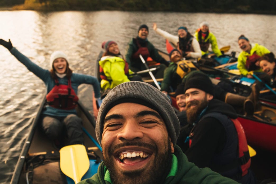 Image of a group of people in canoes smiling with their arms raised