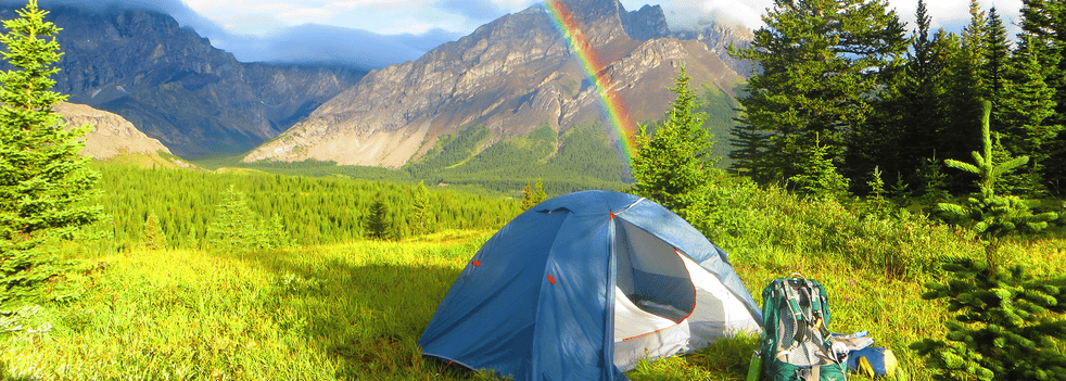 Image of a tent with breathtaking view of rainbow and mountains behind
