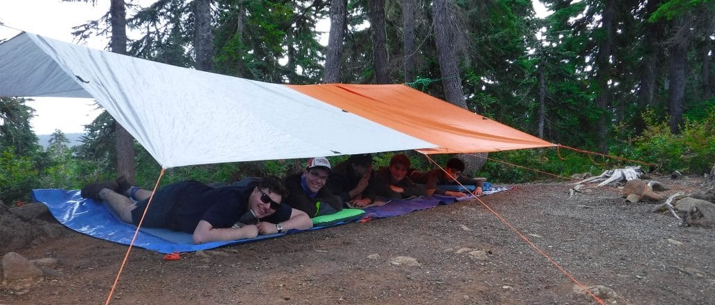 Image of a group of teens laying underneath a shelter made of tarps