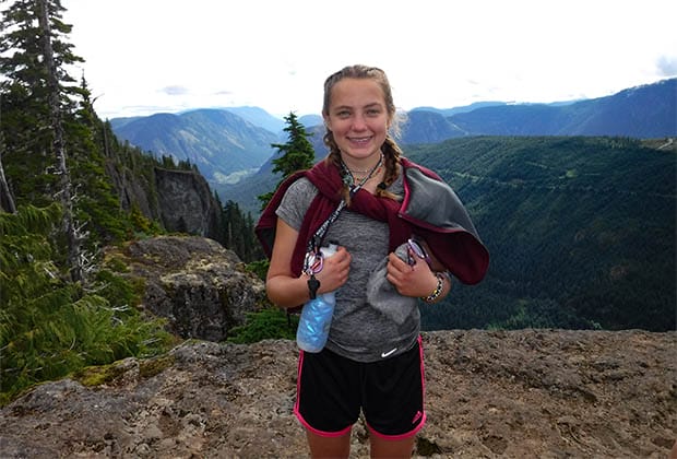 Image of a teen smiling on top of a mountain