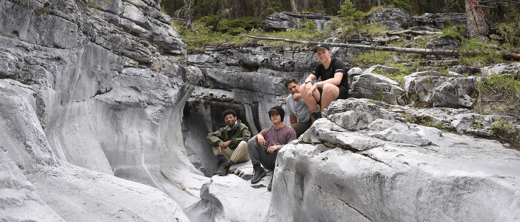 Image of the four persons, sitting in on the cave like structured rocks