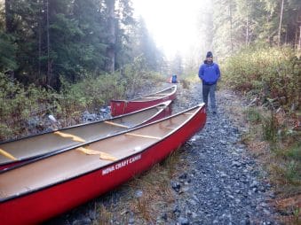 Image of a teen standing next to 3 canoeing on a path