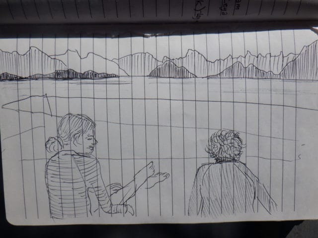 A pen drawing of 2 people sitting by a lake with mountains in the distance
