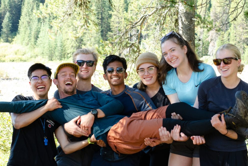 A group of young adults holding one of their friends