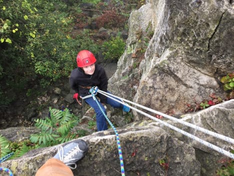 Image of a girl repelling down a rock while wearing a helmet