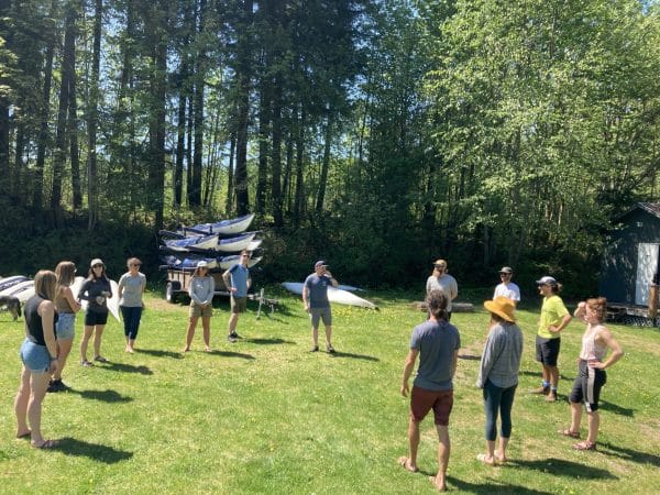 a group of adults standing in a circle in a forest field
