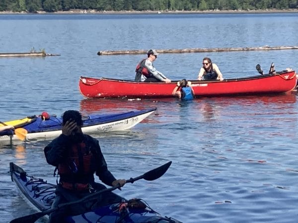 a group of individuals in canoes on the lake, in pairs