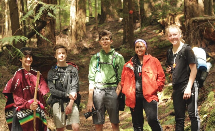 students smiling standing in a BC forest