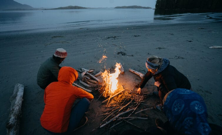Image of 3 people around a campfire on a beach